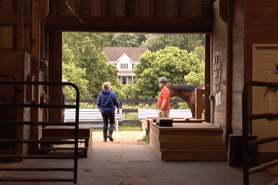 Rider wearing a helmet stands beside a horse inside a barn at an Ohio therapeutic riding nonprofit, filmed by AmeriFilms